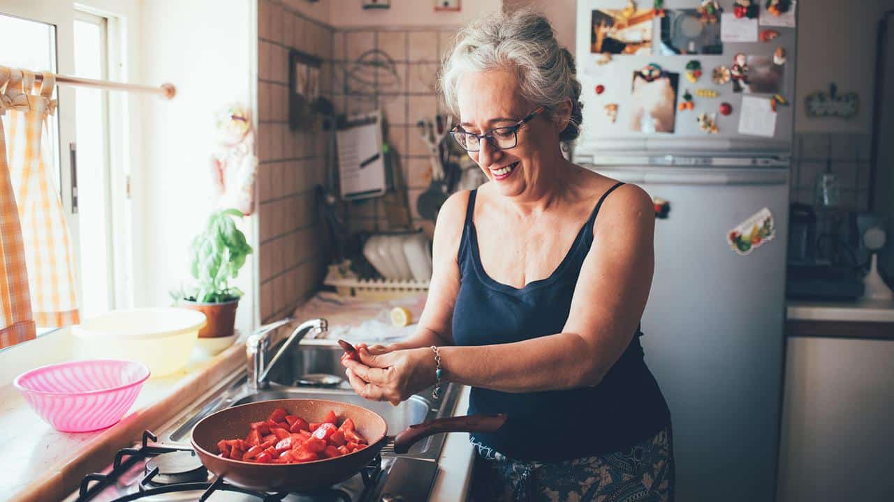 woman smiling making food in kitchen