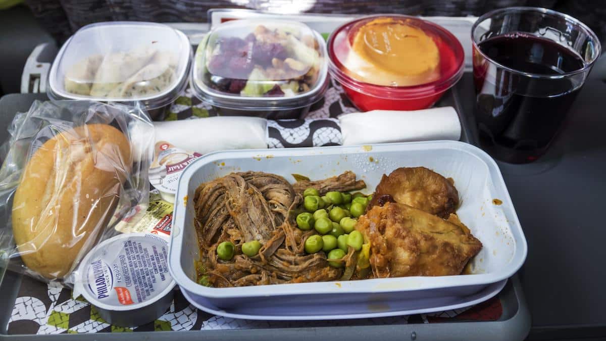 Food packaged in plastic on an airline dinner tray.