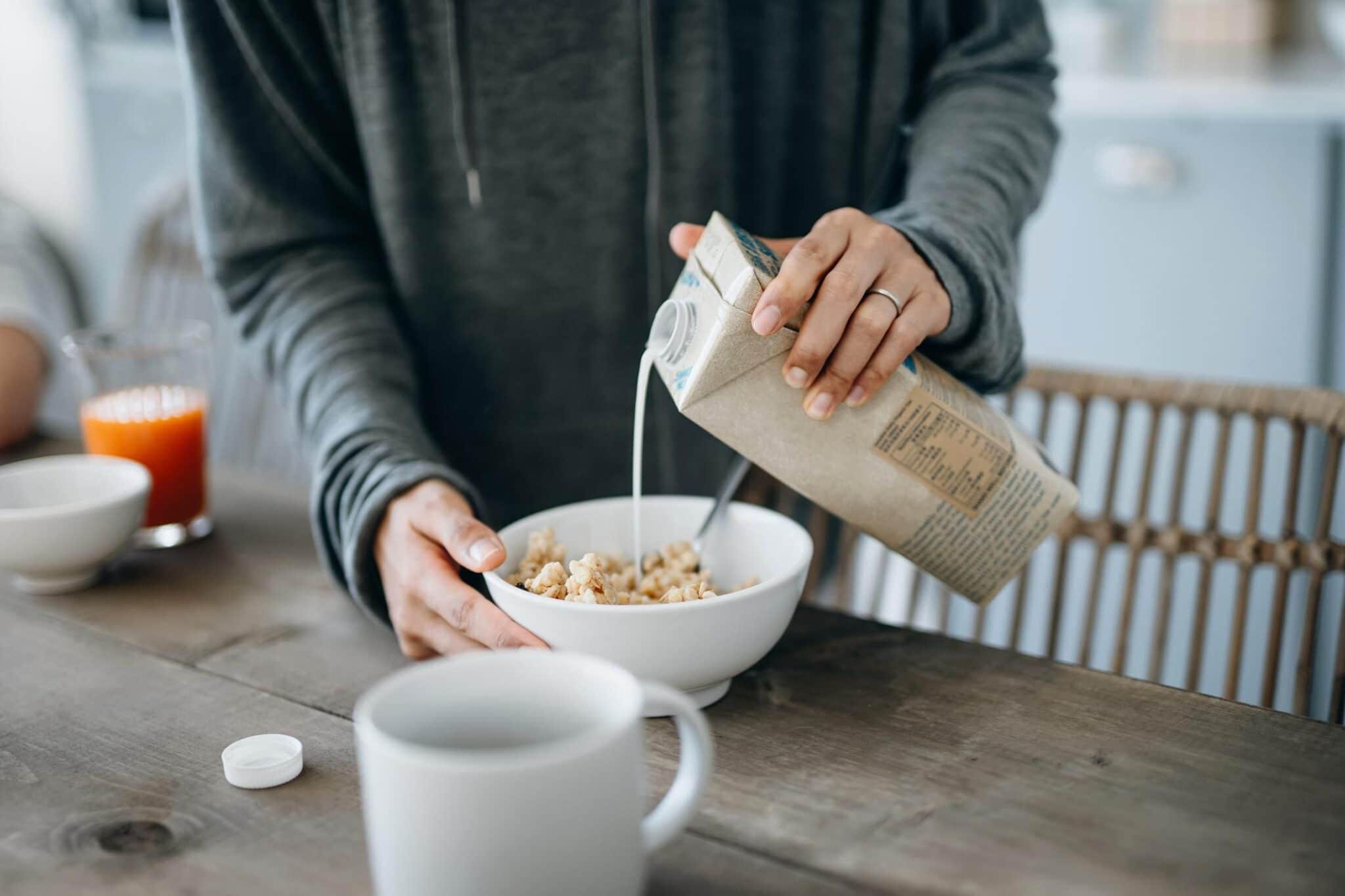 woman pouring milk over cereals on the kitchen counter