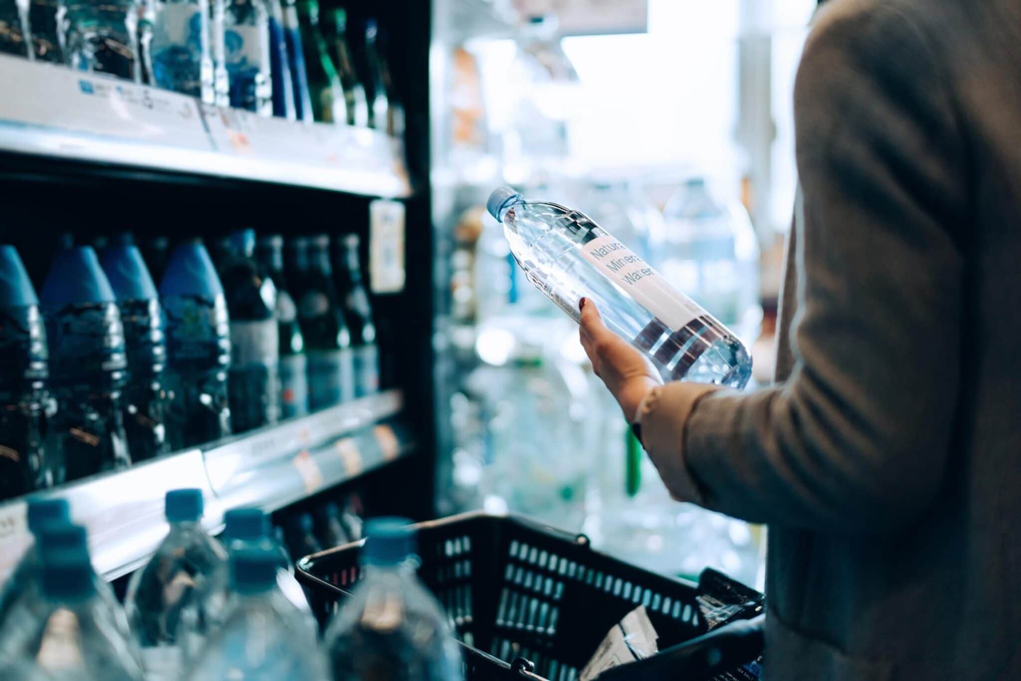 Close up of woman with shopping cart shopping for bottled water along the beverage aisle in a supermarket