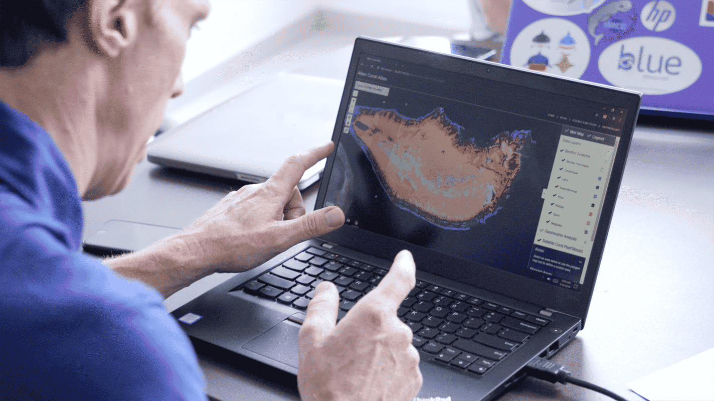An Allen Coral Atlas partner looks at a map on a laptop.