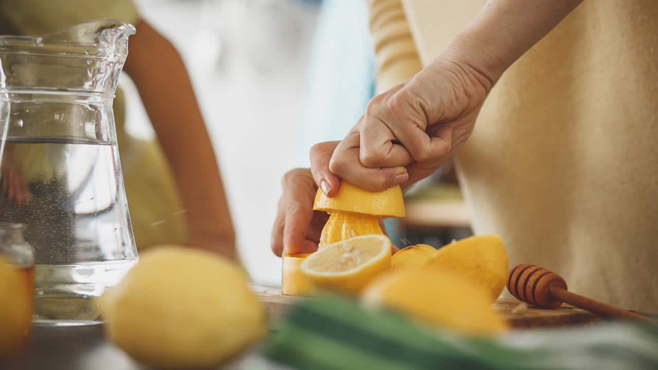 Woman squeezing lemon at the kitchen counter