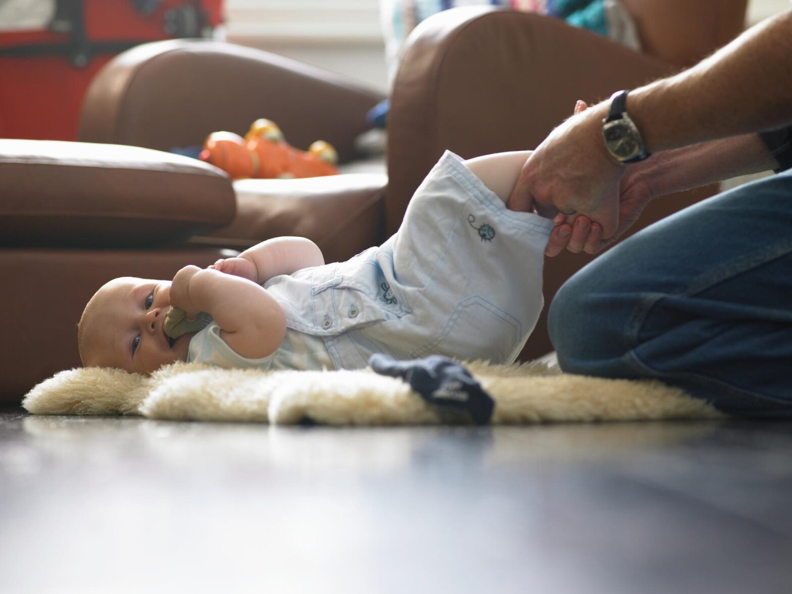 Father changing baby boy (9-12 months) on floor