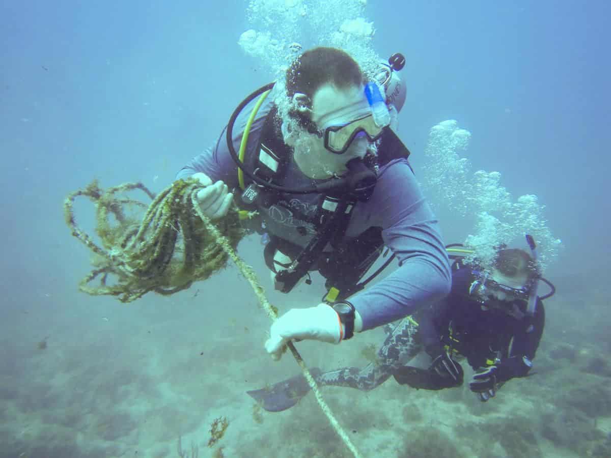 A diver removes and coils ghostline found on a coral reef.