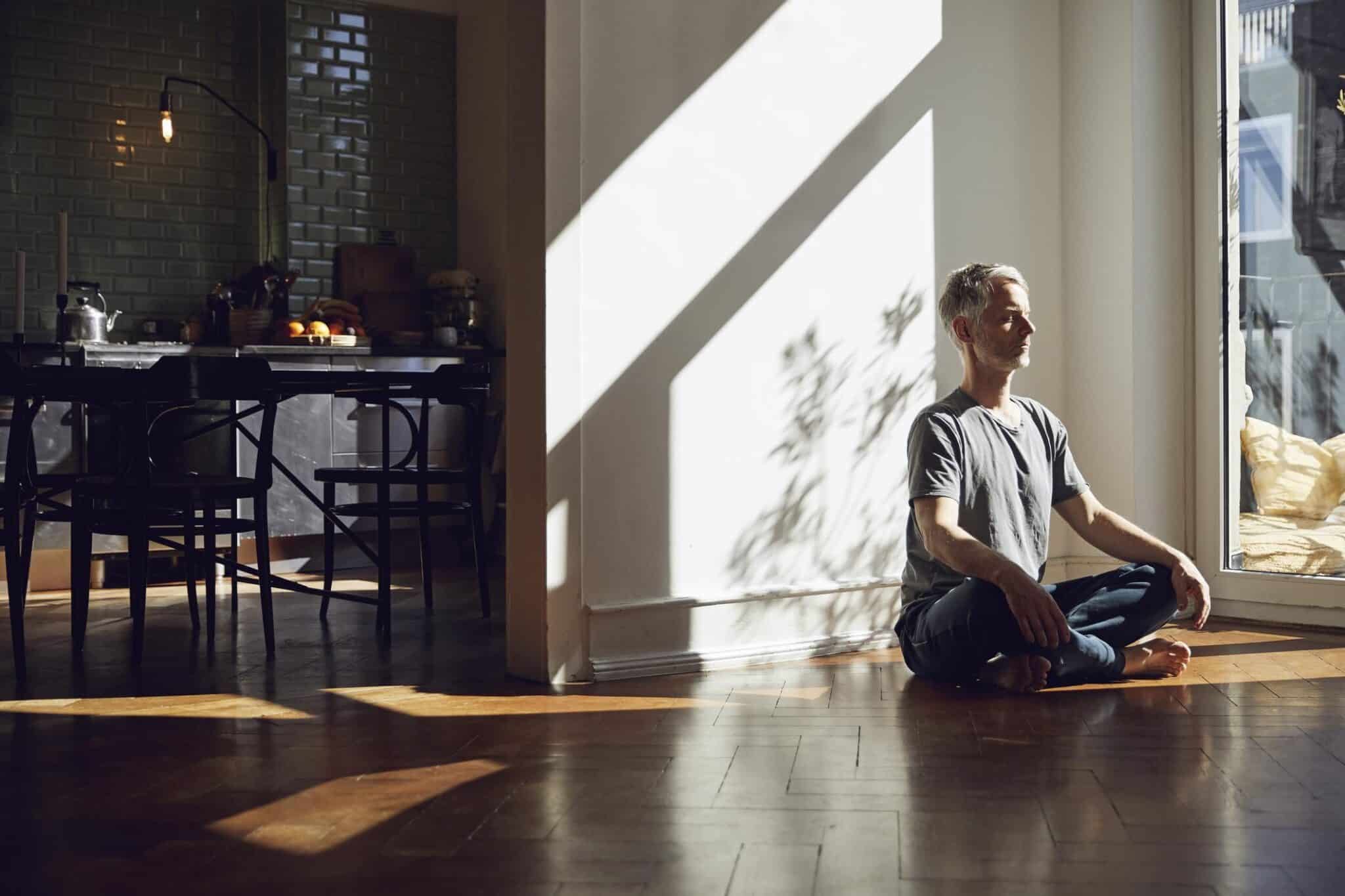  man sitting on the floor at home meditating