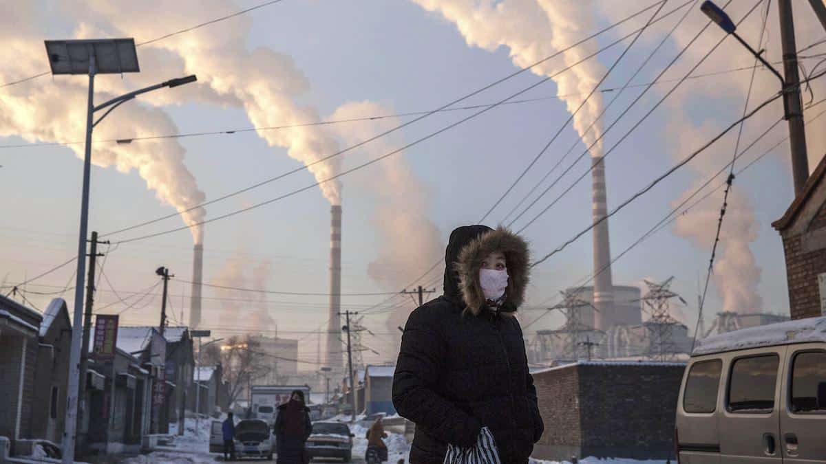 A woman walks near a coal-fired plant in China.