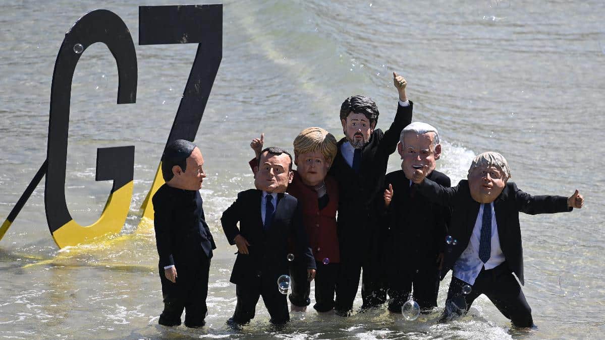 Environmental activists wearing masks of G7 leaders protest on the beach during the G7 summit.