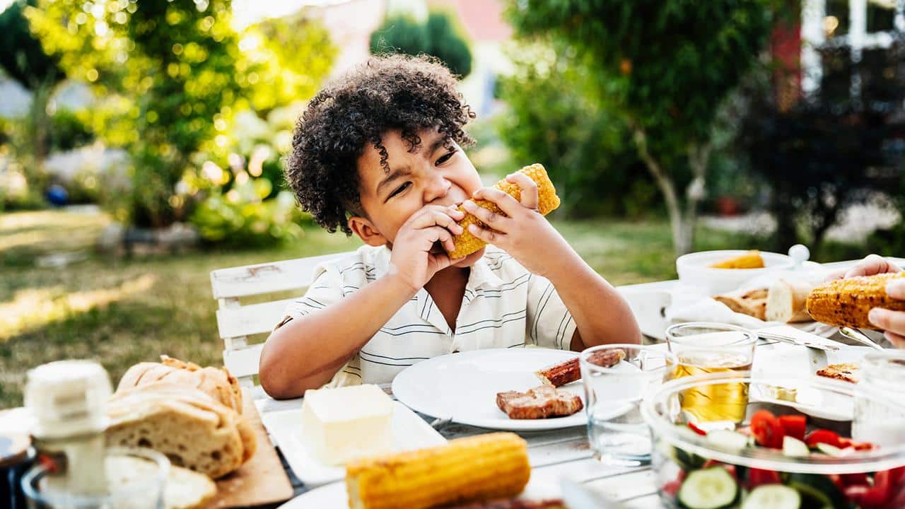 young Boy Eating Barbecued Corn On The Cob