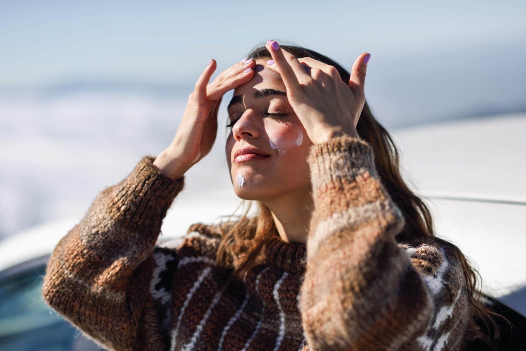 Woman With Eyes Closed Applying Moisturizer While Standing Outdoors During Winter