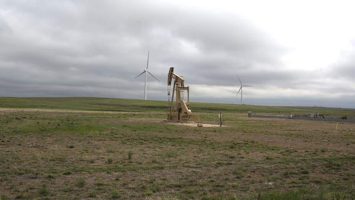 A natural gas pump sits on land next to windmills in rural western Oklahoma.
