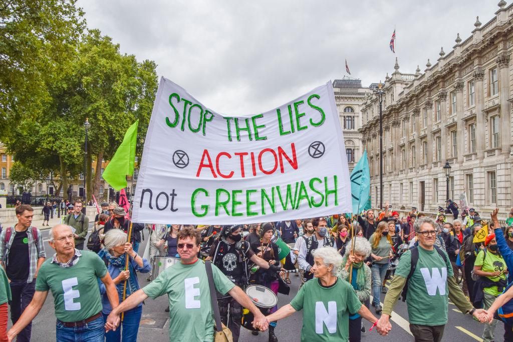 Protesters carry a banner which says 'Stop The Lies - Action...not greenwash.