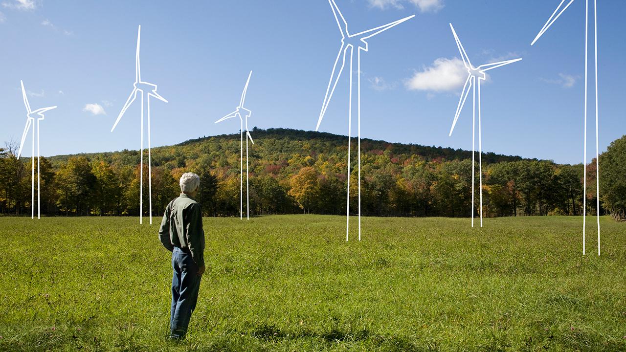 Man in field admiring imaginary wind turbines