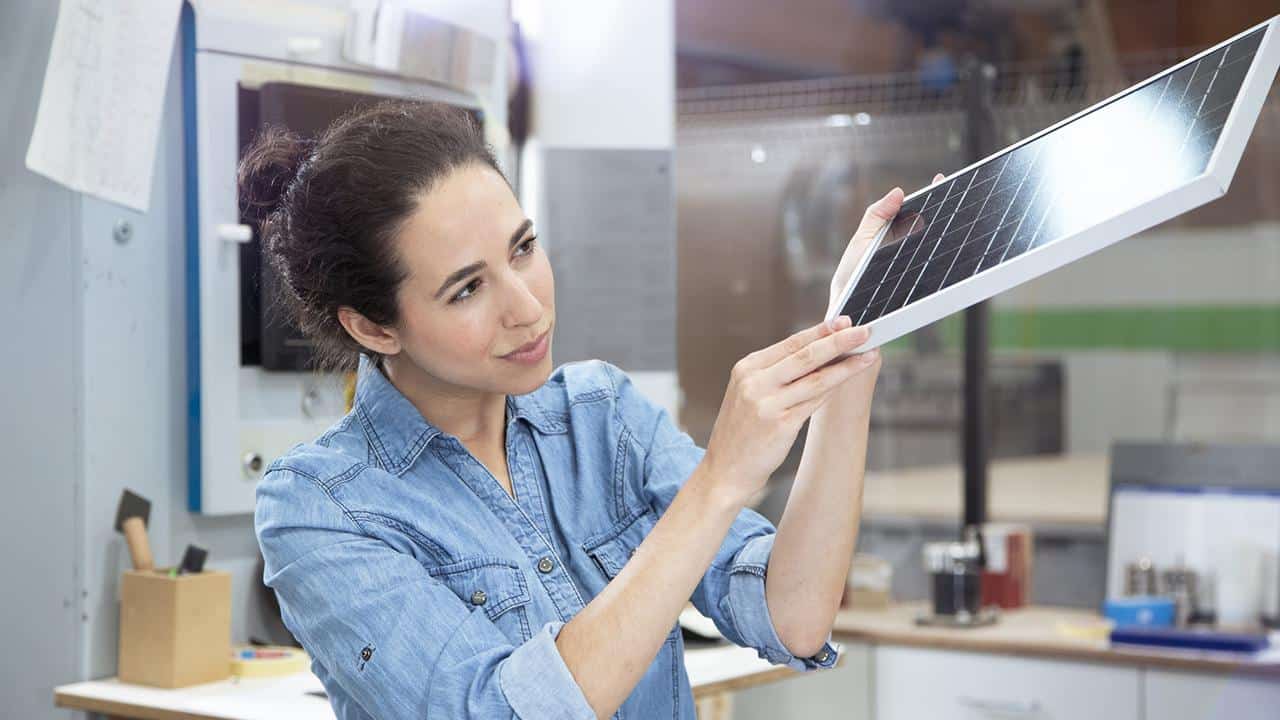 Businesswoman examining solar panel model in factory