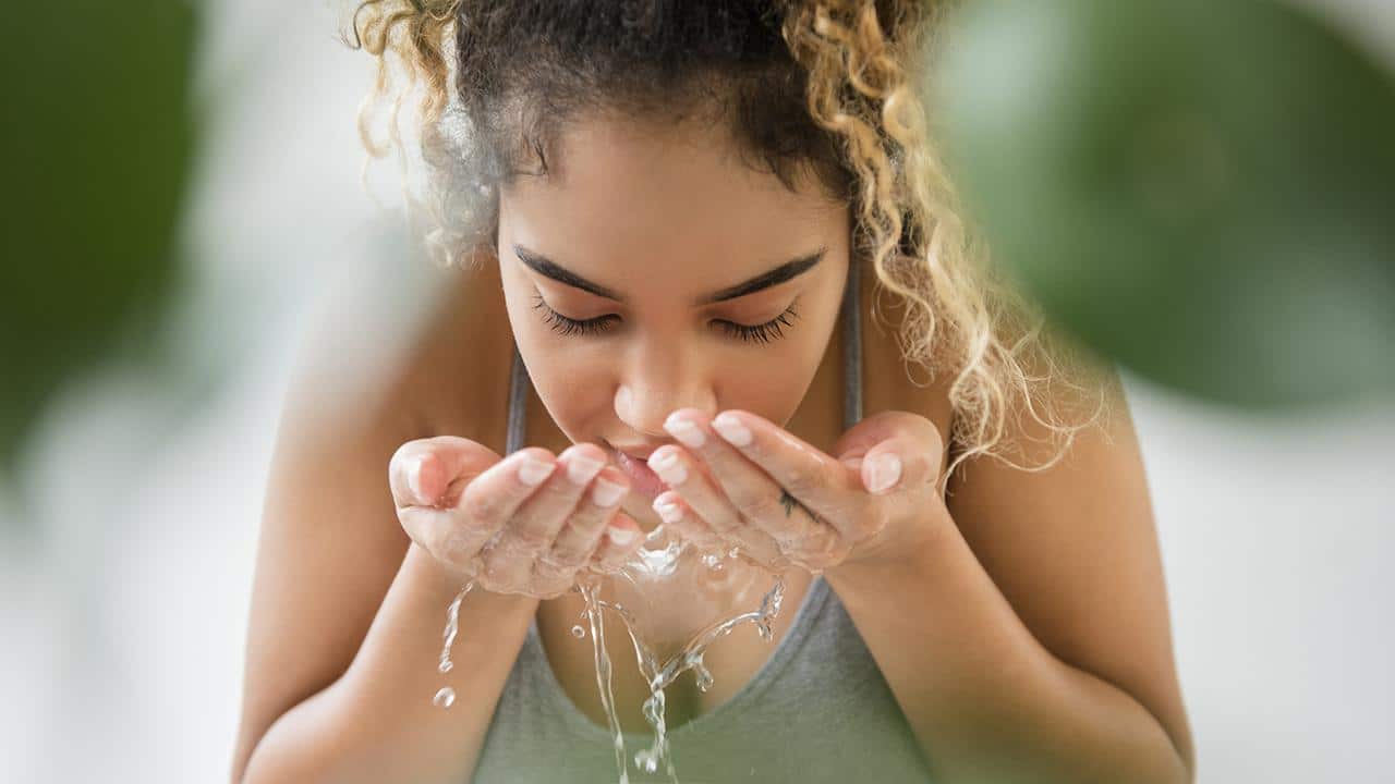 Mixed race woman washing her face