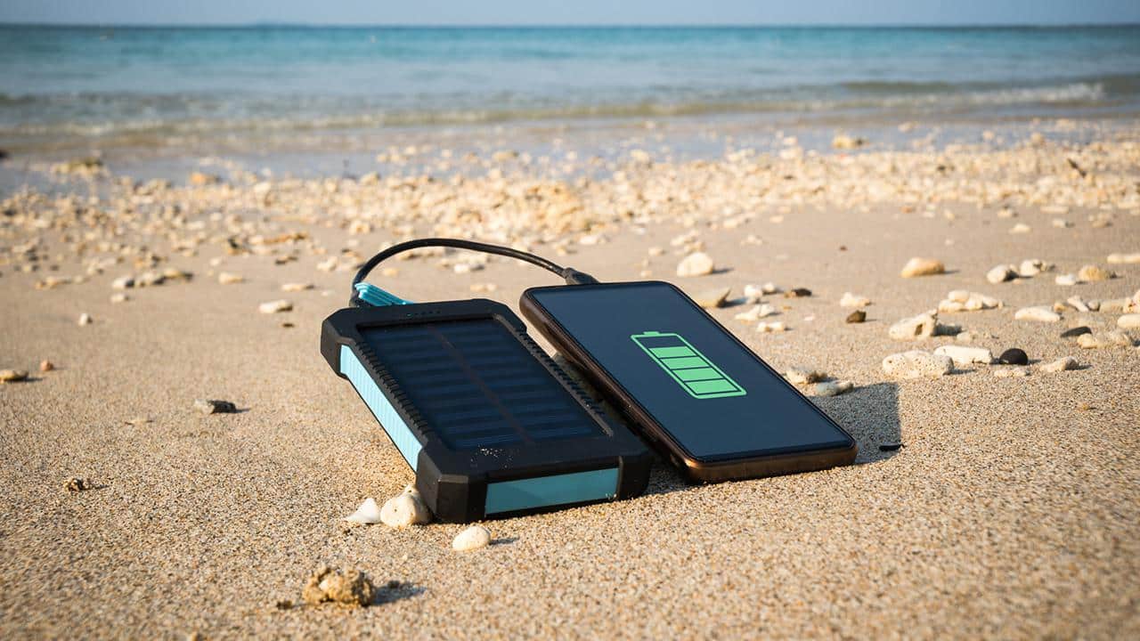 Frameless smartphone close up on a sandy beach with copy space, the concept of restoring strength and energy
