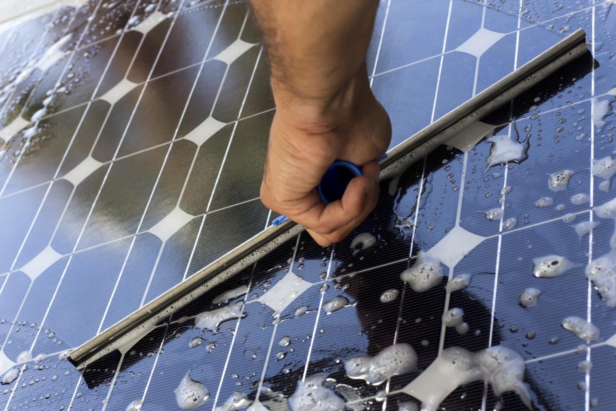 Cleaning solar panels with soapy water and squeegee