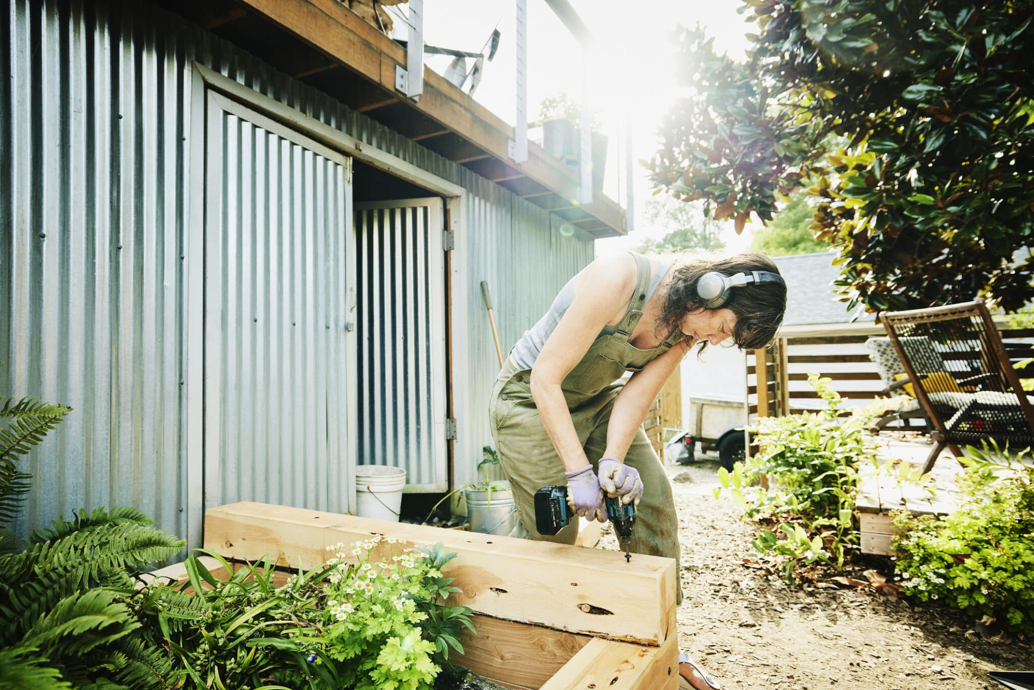 Woman building raised garden beds in backyard on summer afternoon