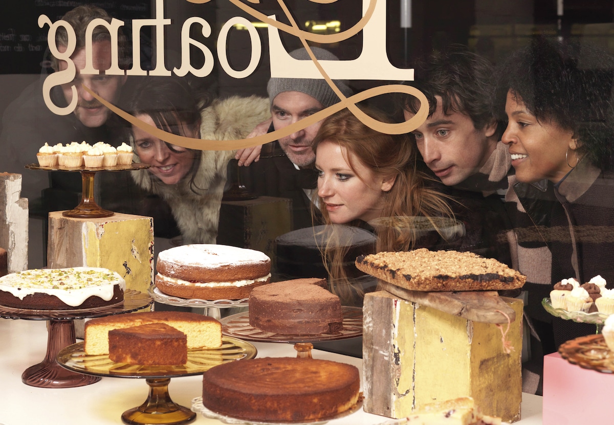 A group of friends looks at pies in a bakery window.