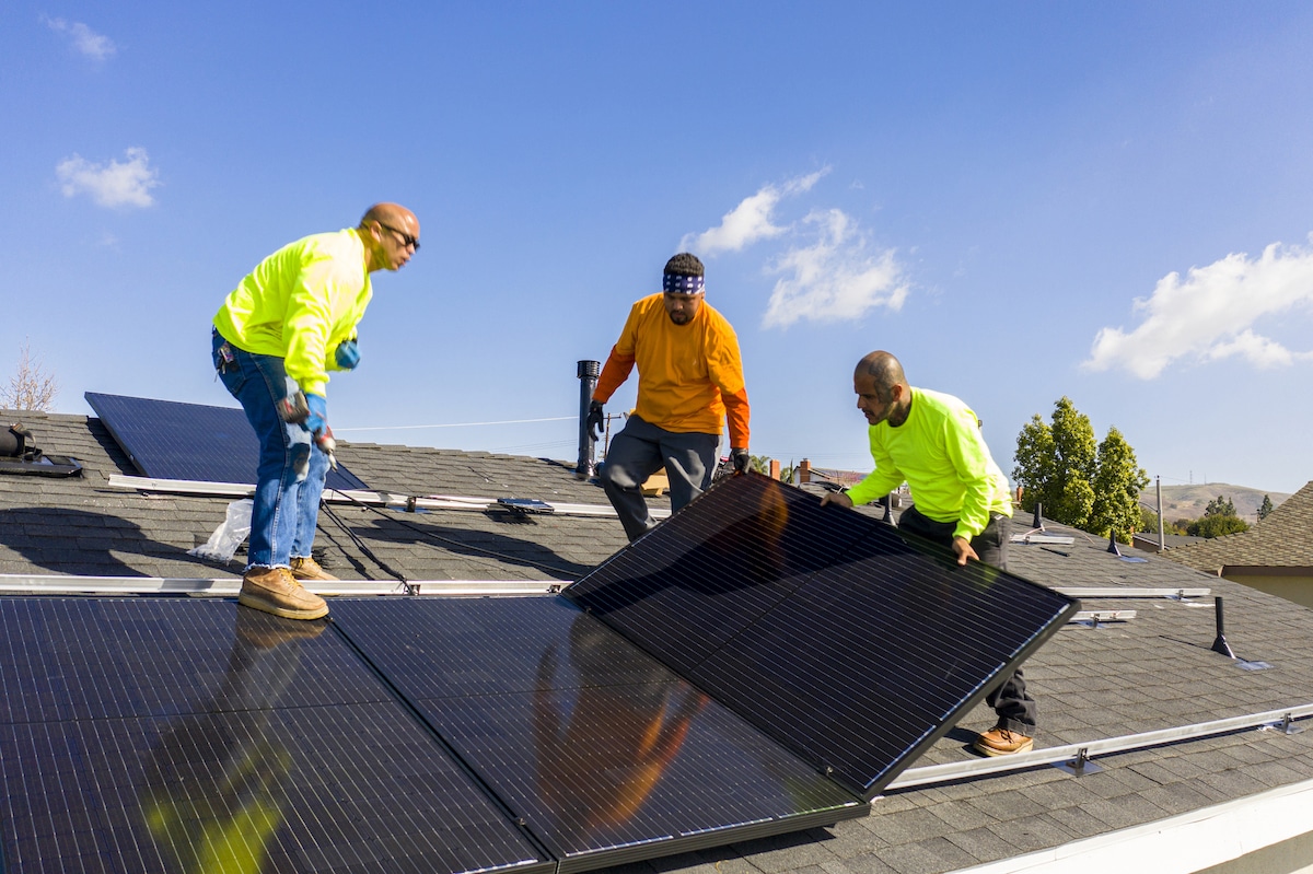Solar workers install panels on a rooftop.
