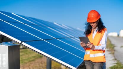 Operation and maintenance in solar power plant ; female engineer, holding notepad, working on checking the solar panels for innovation of green energy for life