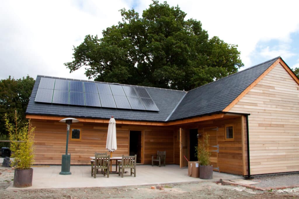 A modern barn conversion with black solar panels on the roof