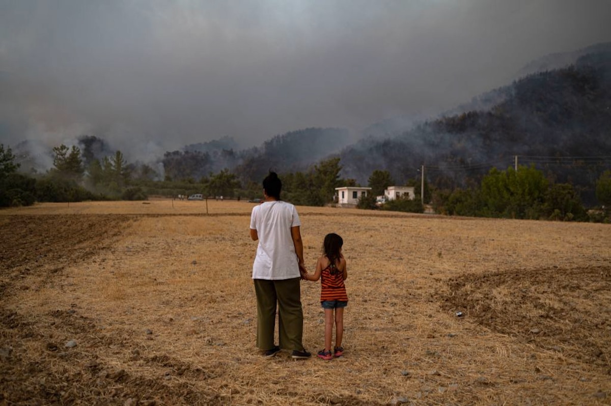 A woman and child watch wildfires burn in Turkey