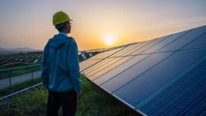 Engineer standing in solar power station looking sunrise