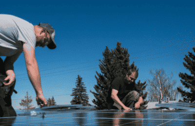 two people installing solar panels on a house