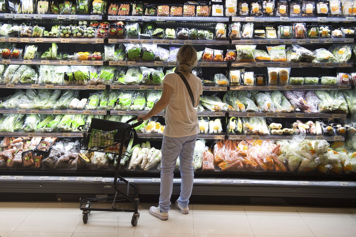 A shopper looks at a shelf of packaged foods at a grocery store