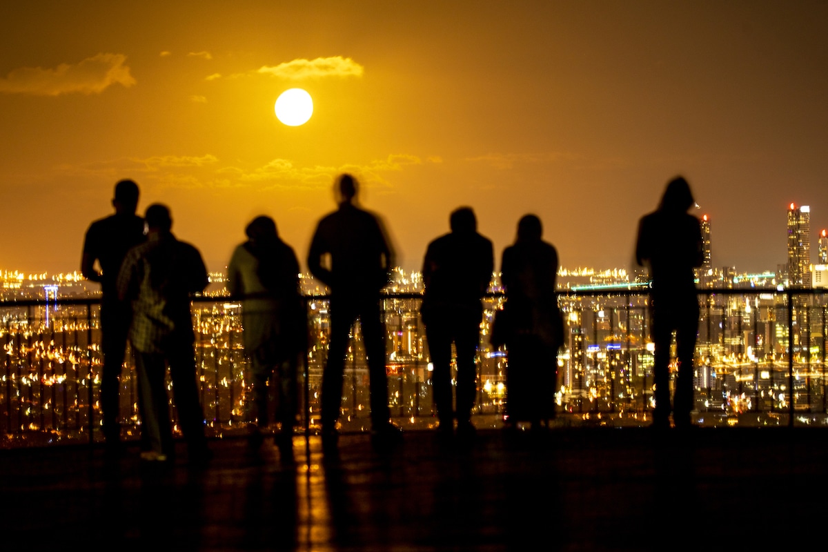 People look out over a warming city at sunset