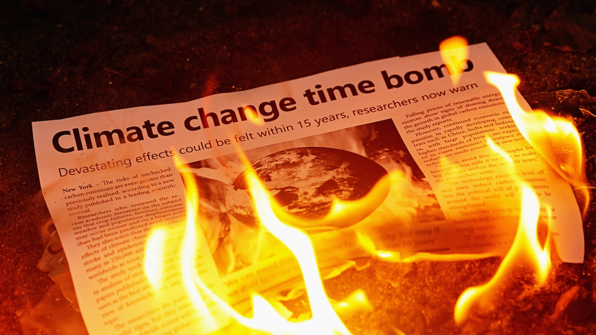 A newspaper with the headline "Climate Change Time Bomb" is on fire