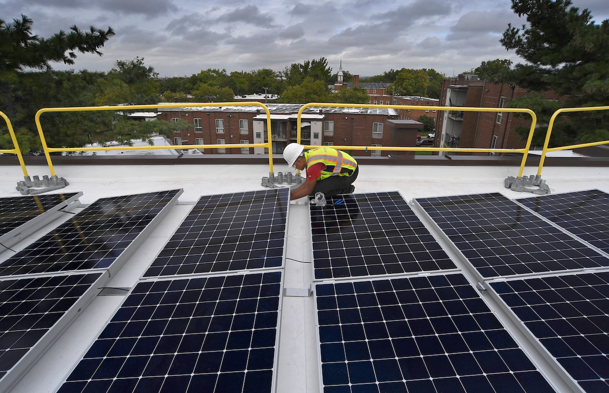 A solar industry worker installs panels on the roof of an apartment complex in Washington, DC.