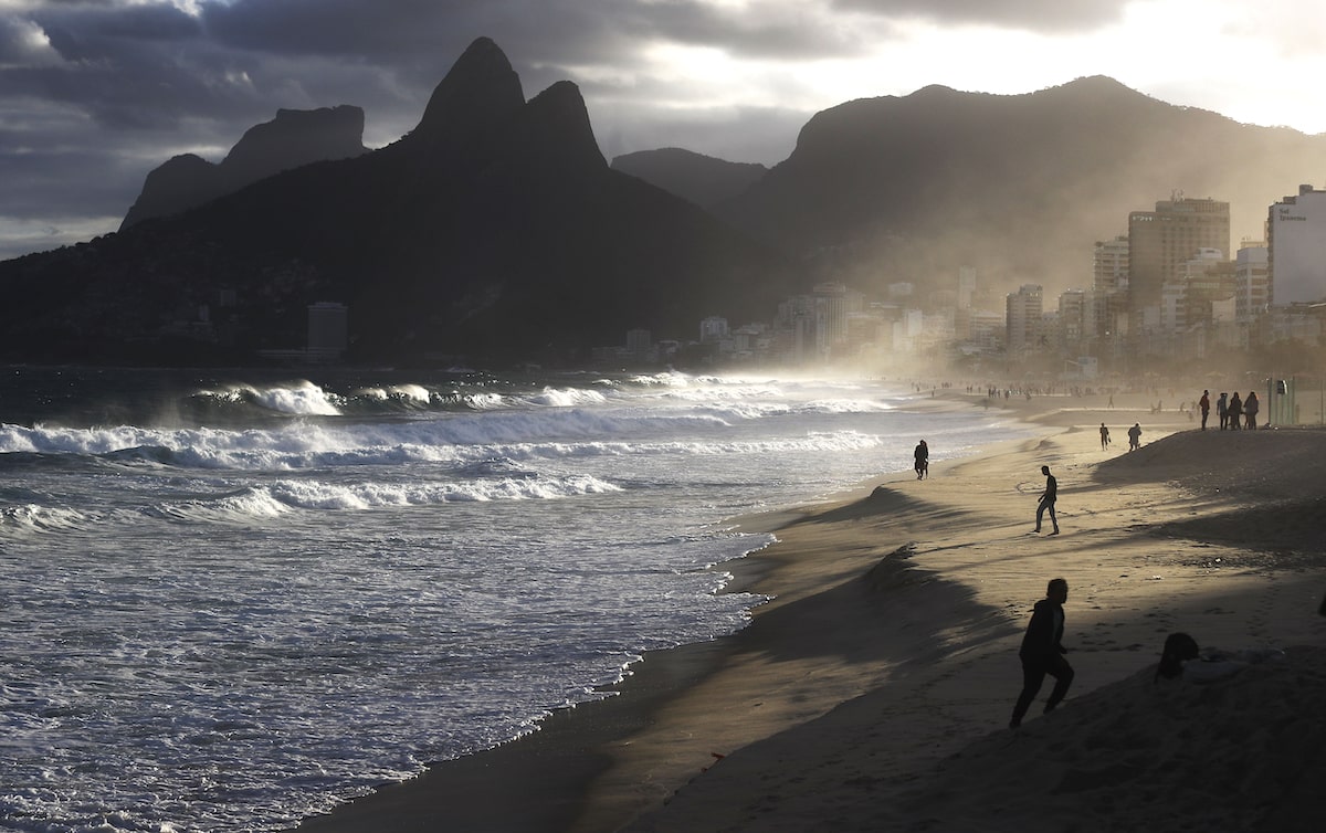 People walk by the Atlantic Ocean on Ipanema beach in Rio de Janeiro, Brazil