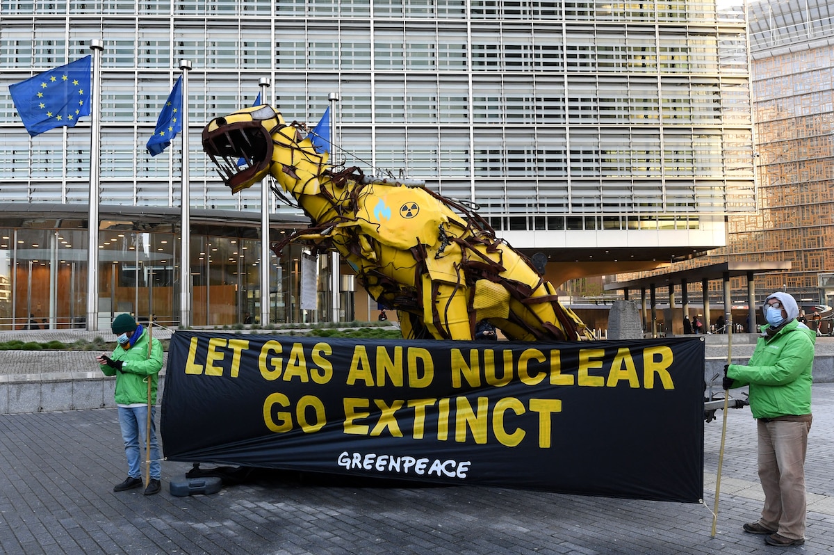 A statue depicting a dinosaur painted with radioactive symbols and blue gas flames is displayed by Greenpeace activists outside the European Commission headquarters in Brussels