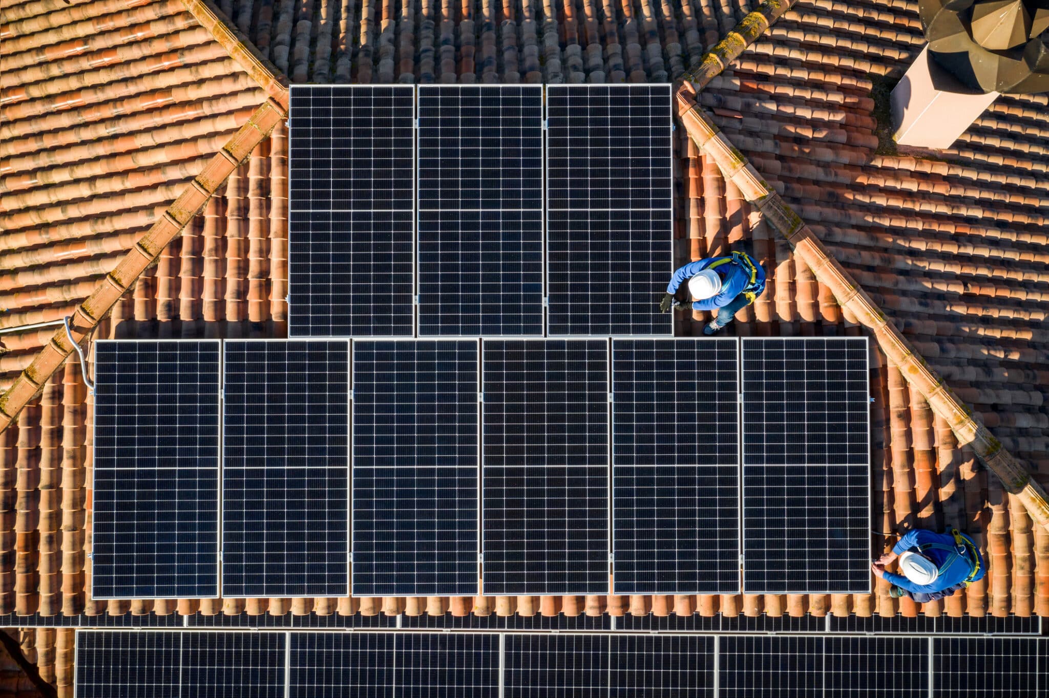 aerial view of Two workers installing solar panels on a house roof
