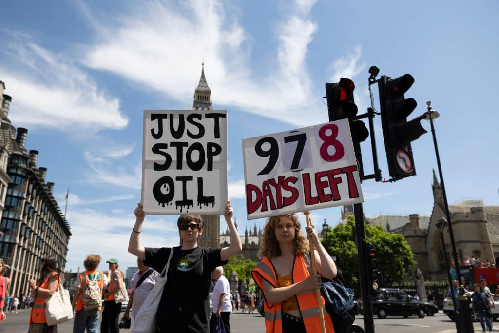Protesters hold placards in front of the UK Parliament