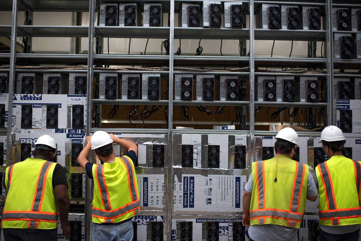 Workers install a new row of Bitcoin mining machines at the Whinstone U.S. Bitcoin mining facility in Rockdale, Texas