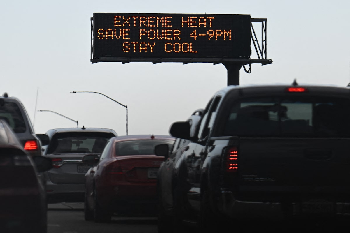 Vehicles drive past a sign on the 110 Freeway warning of extreme heat and urging energy conservation during a heat wave in downtown Los Angeles, California
