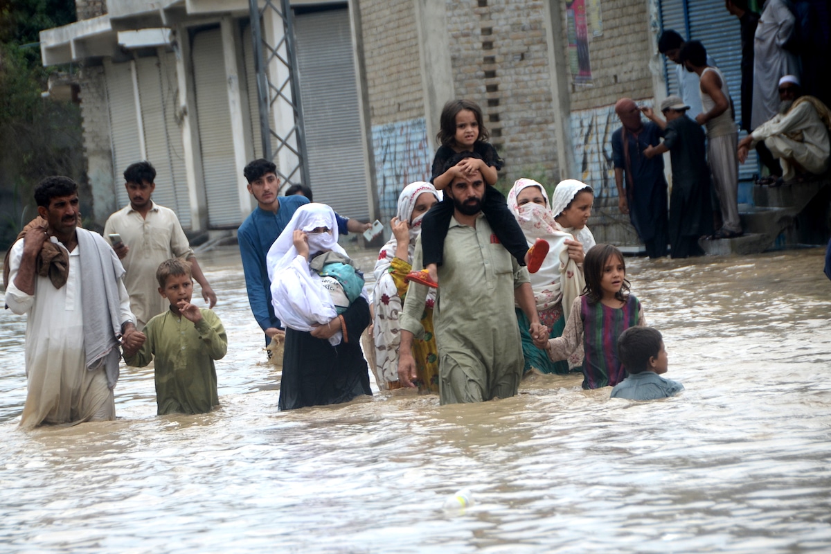 Displaced people wade through a flooded street in Pakistan