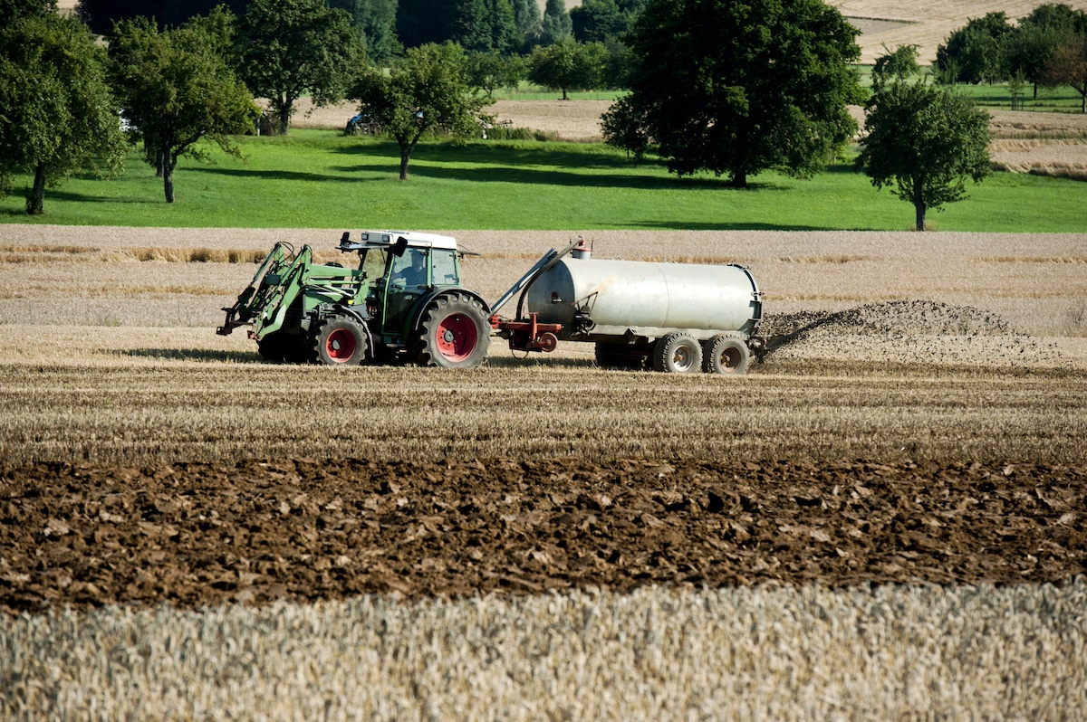 A tractor spreads fertilizer on farmland