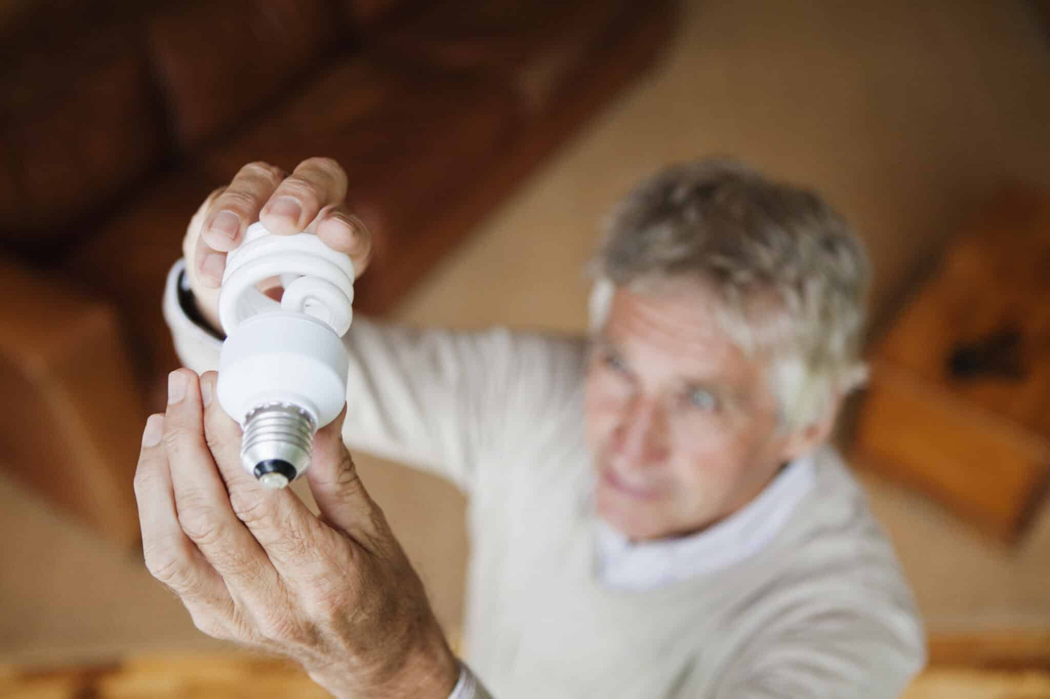 Senior man checking energy efficiency of home light bulbs