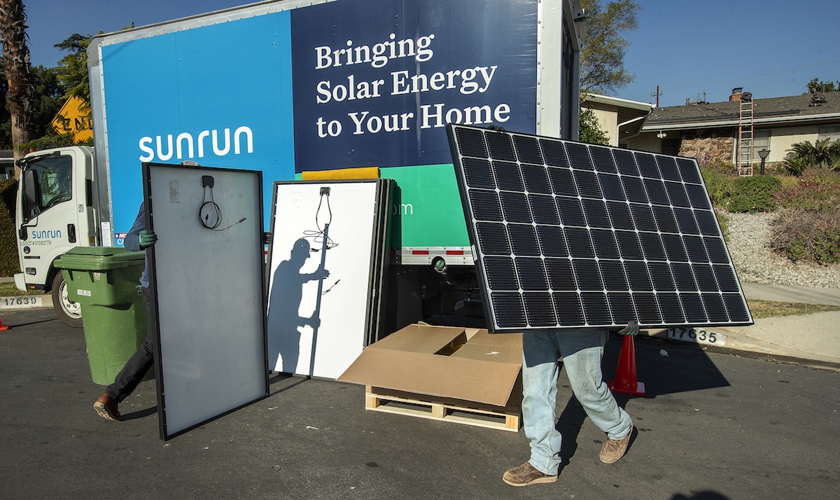 Installers for the solar company Sunrun prepare solar panels to be installed on the roof of a home in California