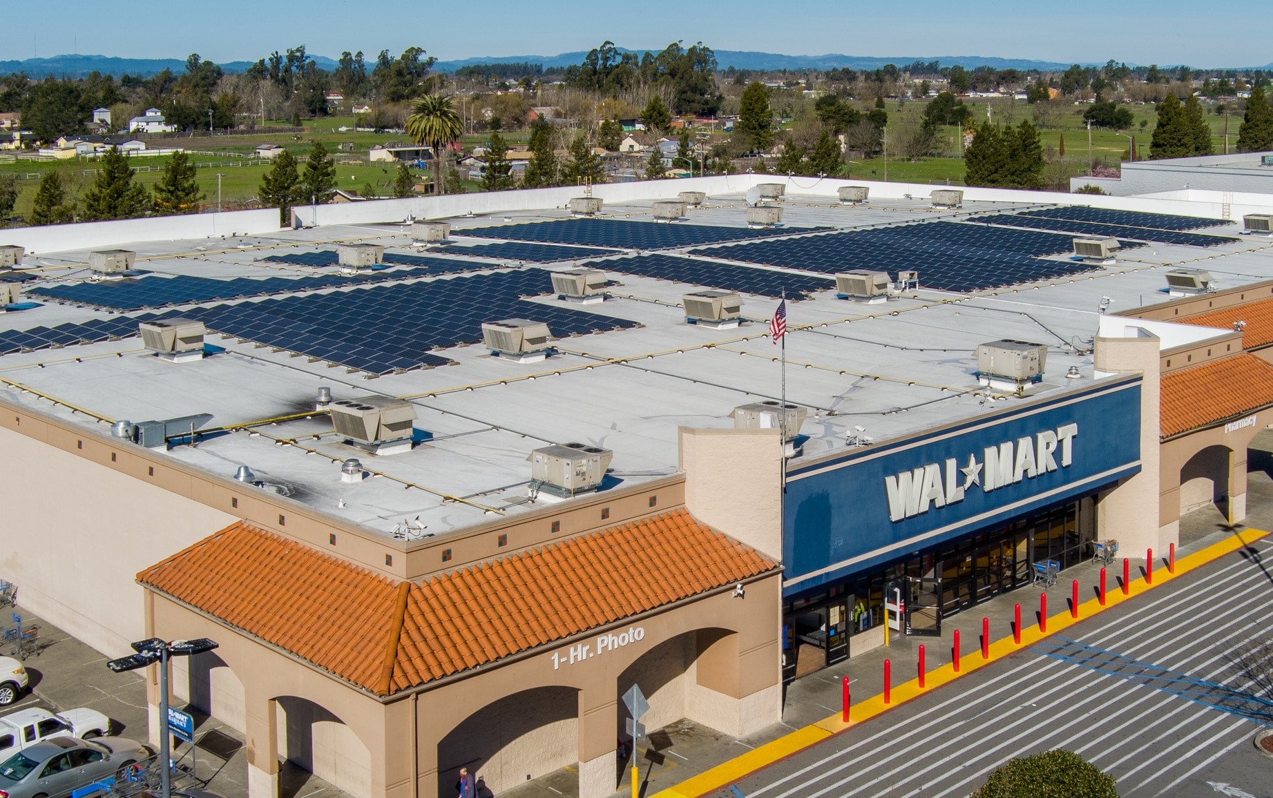 An aerial of a Walmart store in Northern California with signage logo at the front entrance. The store has solar panels on the roof.