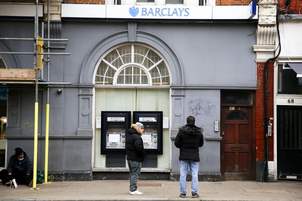 Members of public wait outside a branch of Barclays Bank to