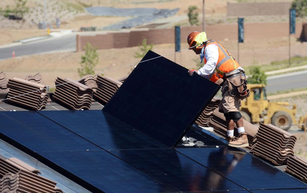 worker installing solar panels on roof