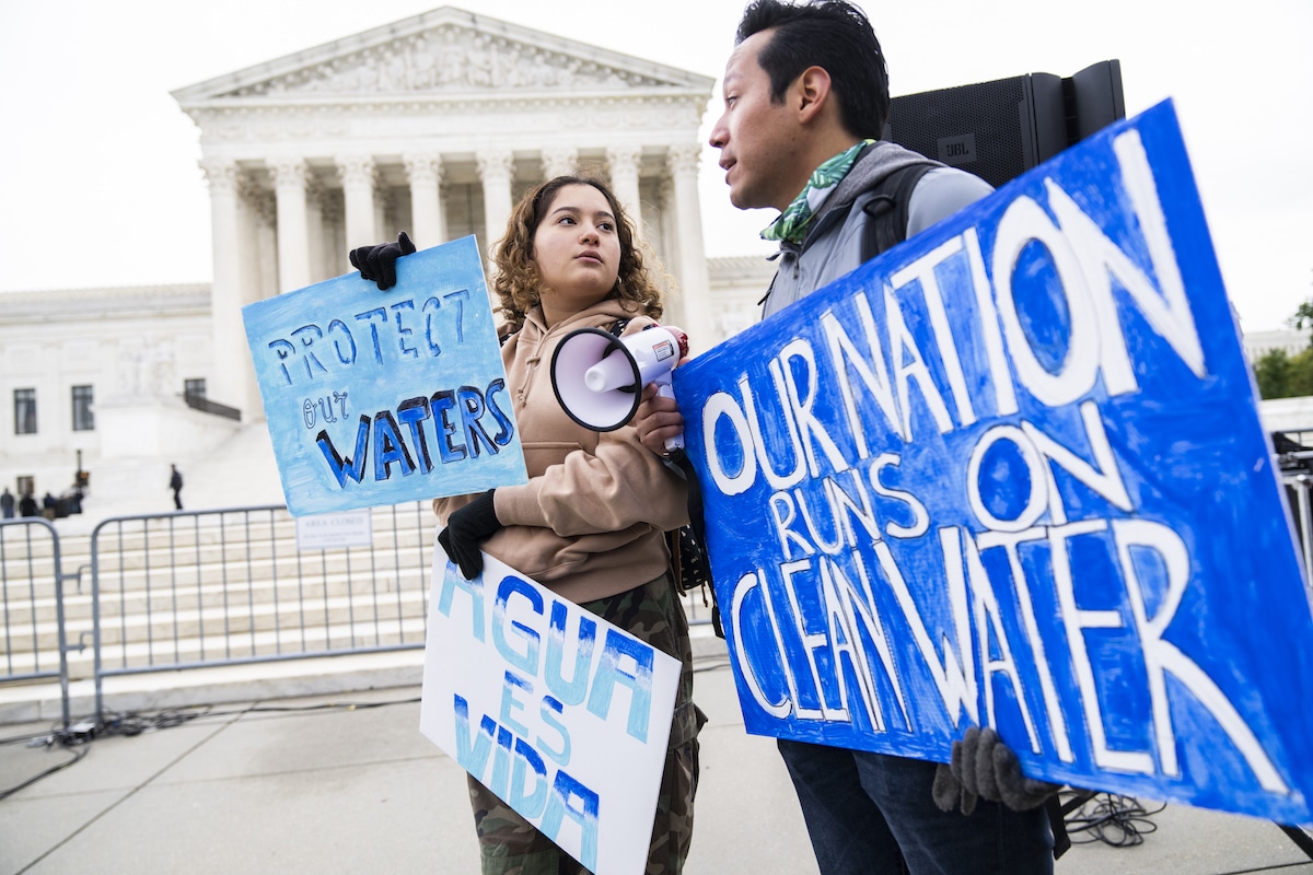 Clean water advocates hold signs calling for protection of the Clean Water Act outside of the U.S. Supreme Court