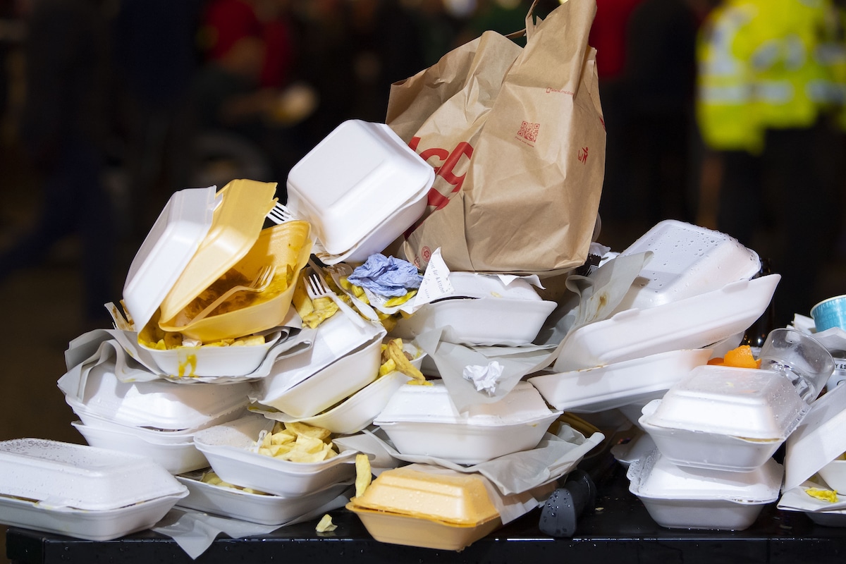 An overflowing bin of Styrofoam takeaway food containers and plastic utensils in Cardiff, UK