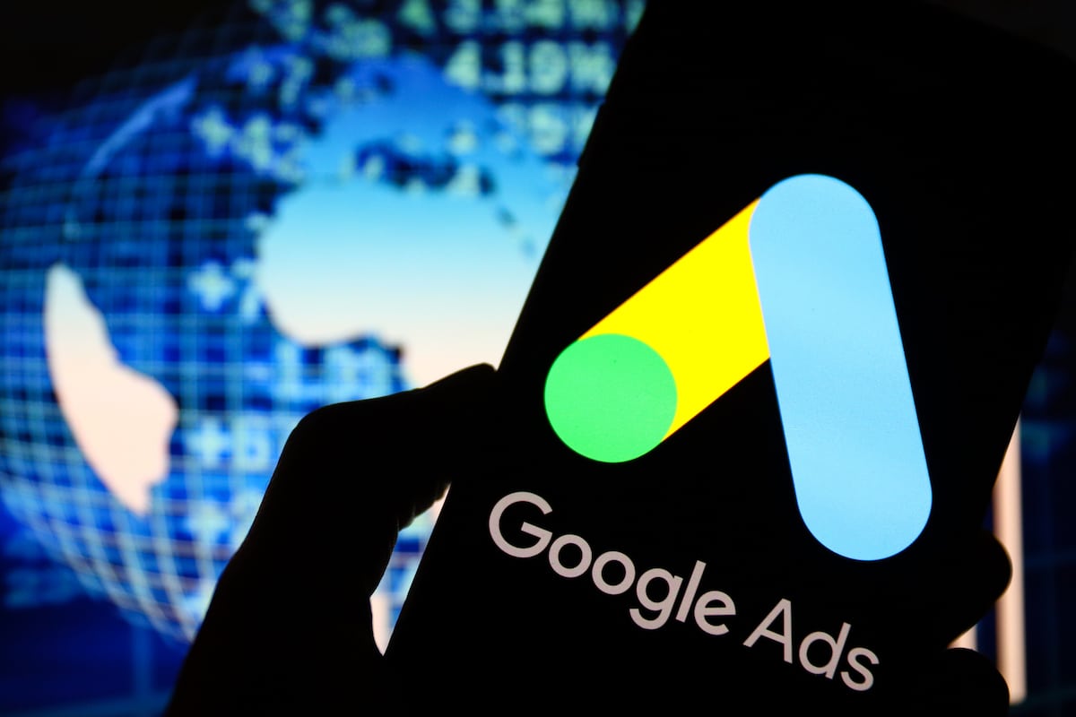 A Google Ads logo displayed on a smartphone with blue world data stats in the background