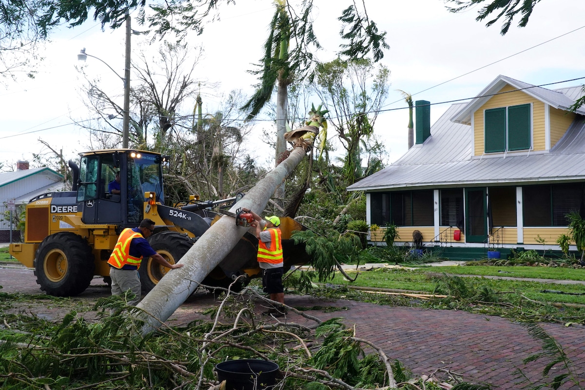 A road crew attempts to remove a fallen palm tree from a power line in Punta Gorda, Florida, following Hurricane Ian