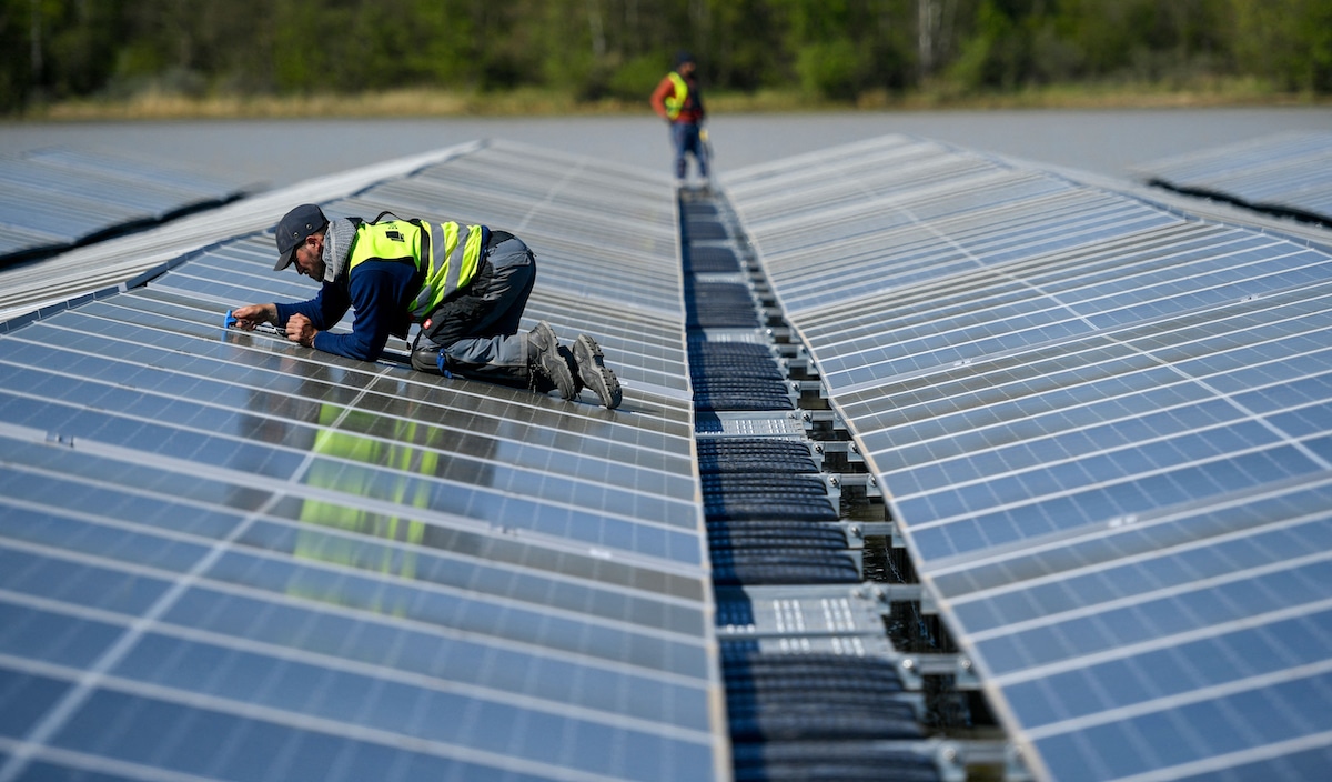 Workers install solar panels for a floating photovoltaic solar plant in Germany